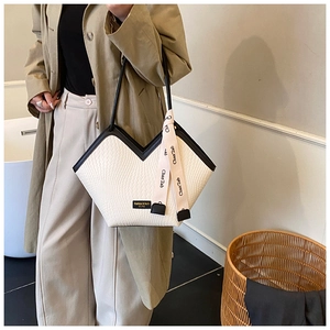 Détail du sac cabas tissé avec ouverture en V, liseré noir contrasté et ruban de soie