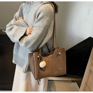 Brown leather tote bag featuring a plush ice cream charm and stylish vertical stitching