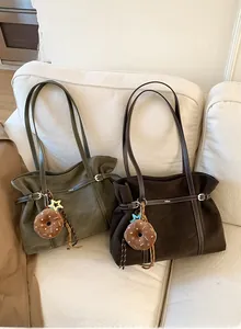 Close-up of minimalist suede tote bags in green and brown with plush donut charms