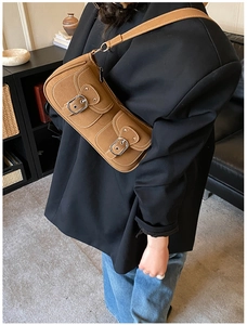 Close-up of vintage brown shoulder bag with dual pockets and metal buckle details
