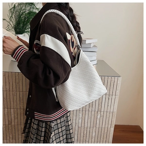 Detail of white woven hobo bag showing intricate V-pattern texture and braided strap