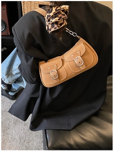 Detail view of vintage tan suede shoulder bag with dual buckle pockets and contrast stitching