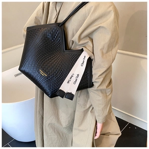 Détail de sac cabas tressé noir avec ouverture en V et sangle décorative élégante