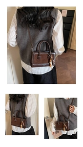 Detail of vintage brown leather handbag featuring wooden bead charm and logo print