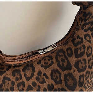 Detail shot of the silver metal zipper and soft leopard print texture of the bag