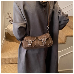 Detail of vintage brown suede shoulder bag featuring double front pockets and white stitching