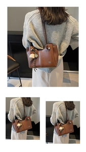 Detail of brown leather tote bag with stylish ice cream pendant and embossed branding