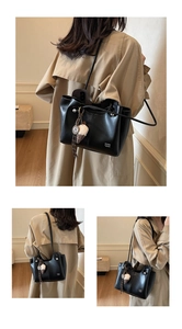 Detail of large black leather tote bag with silver hardware and plush ice cream charm