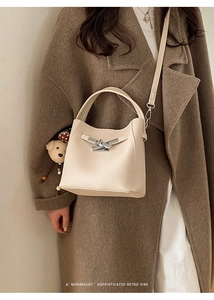Close-up of cream lychee leather bucket bag with silver clasp and teddy bear charm