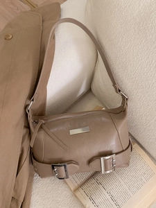 Vintage khaki leather shoulder bag with decorative silver buckle on minimalist background