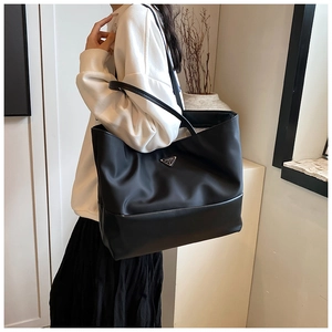 Close-up of the large black tote bag featuring nylon and leather splicing with metal logo
