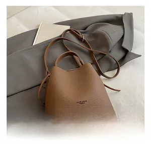Secchiello in pelle testa di moro con trama litchi e logo del marchio in un set lifestyle