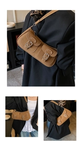 Detail of brown leather underarm bag featuring white contrast stitching and silver buckles