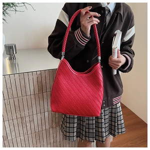 Detail of red woven hobo bag showing intricate V-pattern texture and shoulder strap