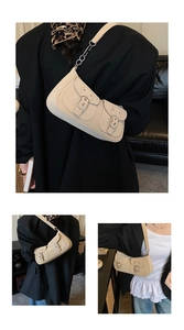 Detail of beige shoulder bag featuring dual buckle pockets and silver metal chain strap