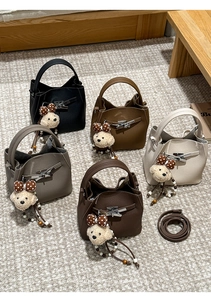 Detail of five litchi grain bucket bags with metal buckles and cute teddy bear charms