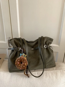 Minimalist olive green suede tote bag with contrast stitching and plush charm