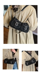 Detail of black vintage shoulder bag with white contrast stitching and silver metal buckles