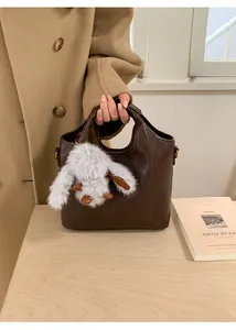 Detail view of retro brown leather bucket bag with a cute white plush bunny charm