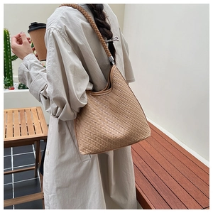 Close-up of beige woven bucket bag with detailed textured pattern and round shoulder strap