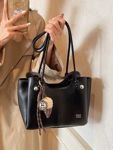 Fashionable black leather tote bag with plush charm and metal logo for casual wear