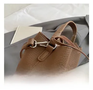 Dettaglio del gancio girevole in metallo argento e della tracolla in pelle marrone borsa