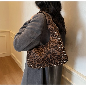 Detail view of leopard print hobo bag with silver studs on textured fabric