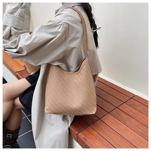 Detail of woven light brown hobo bucket bag showing premium texture and shoulder strap