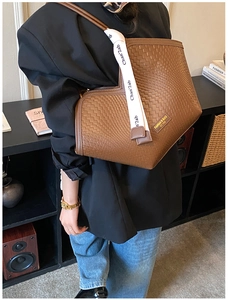 Détail de la texture tressée du sac cabas marron avec ruban et étiquette décorative