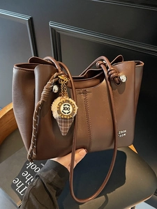 Chic brown leather tote bag with ice cream plush charm and minimalist dual handles