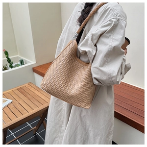 Detail of light brown woven bucket bag showing premium leather texture and silver buckle