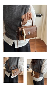 Close-up of brown vintage PU leather handbag with silver square lock and beaded tassel