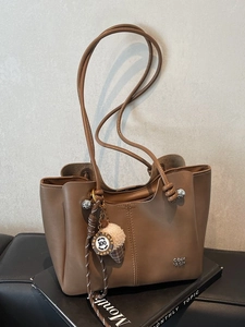 Brown leather tote bag with silver logo and ice cream charm on a stylish background