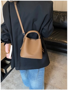 Borsa a secchiello in pelle marrone martellata abbinata a un blazer nero elegante