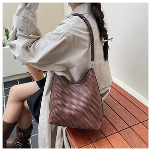 Detail of dark coffee woven hobo bag with V-shaped texture and matching shoulder strap