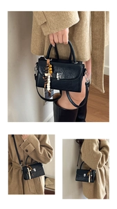 Detail of black crossbody bag with colorful wooden beads and silver metallic buckle