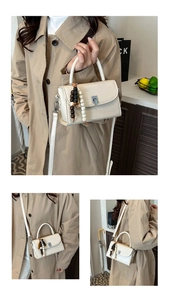 Detail of cream PU leather handbag featuring silver clasp and vintage beaded charm