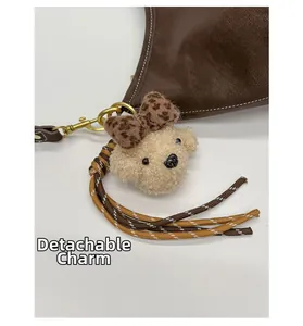 Removable plush puppy pendant with leopard bow and braided tassel on a brown bag