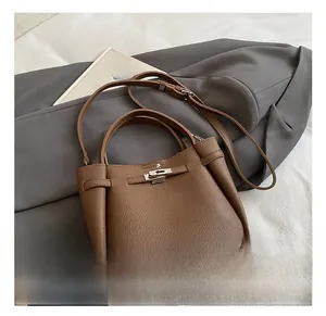 Detail of brown litchi pattern leather bucket bag featuring silver twist lock and strap