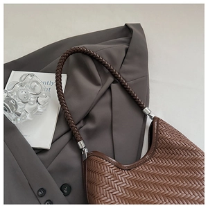 Detail of brown woven hobo bag texture with silver metallic hardware on grey blazer