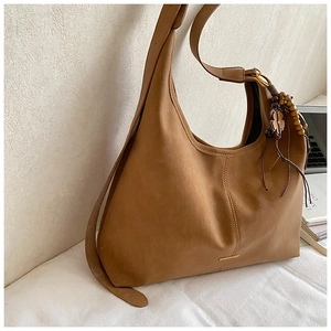 Detail of vintage brown suede tote bag featuring a floral wooden bead charm and metal trim