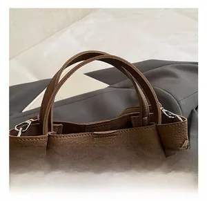 Close-up of brown lychee leather bucket bag with silver metal buckle and handle