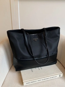 Large black Oxford tote bag with leather splice and triangular logo on white sofa
