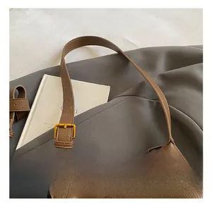 Détail de la texture cuir marron et boucle en métal doré sur un sac seau élégant