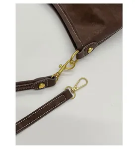 Detail of dark brown leather texture with high-quality gold hardware hook and D-ring