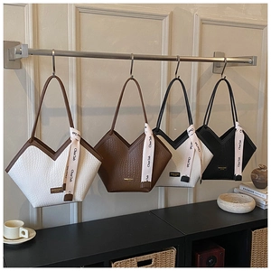 Détail de quatre sacs cabas texturés en blanc, marron et noir avec rubans de satin élégants