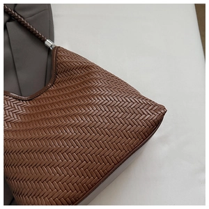 Detail of woven brown leather shoulder bag with intricate Intrecciato pattern and texture