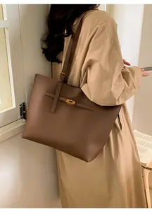 Detail of dark brown pebble leather tote bag featuring a gold twist-lock and shoulder strap