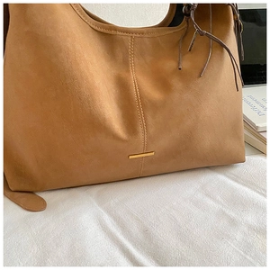 Macro shot of brown suede tote bag featuring minimalist gold hardware and vintage details