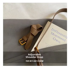 Détail d'une bandoulière en cuir grainé avec boucle réglable dorée sur sac seau